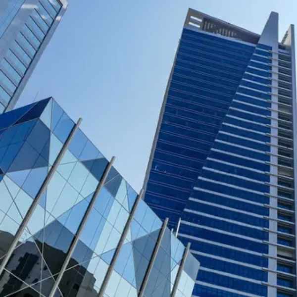 Modern glass skyscrapers reflecting the sky in an urban setting.